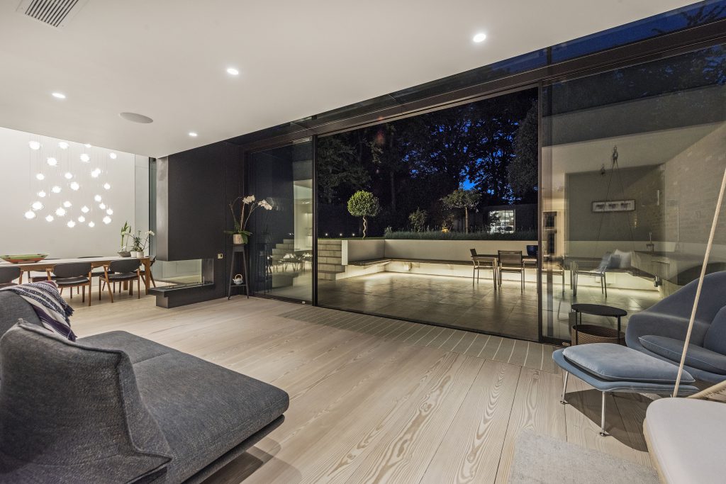 Open-plan living and dining room with sliding doors onto a lit terrace